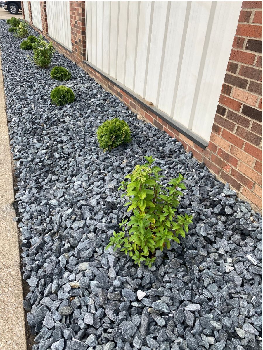Crew spreading decorative gray rock in new planting bed